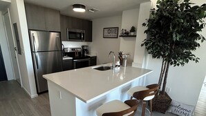 Uma cozinha moderna com uma ilha central, eletrodomésticos de aço inoxidável e uma grande planta em vaso.