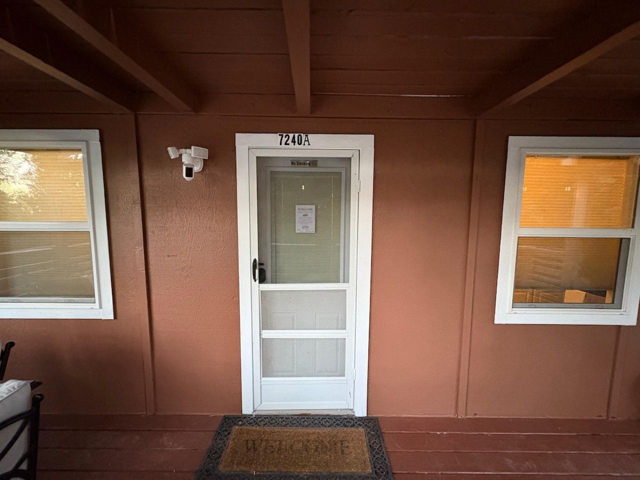 A front door with a number plate, a welcome sign, and a doormat.