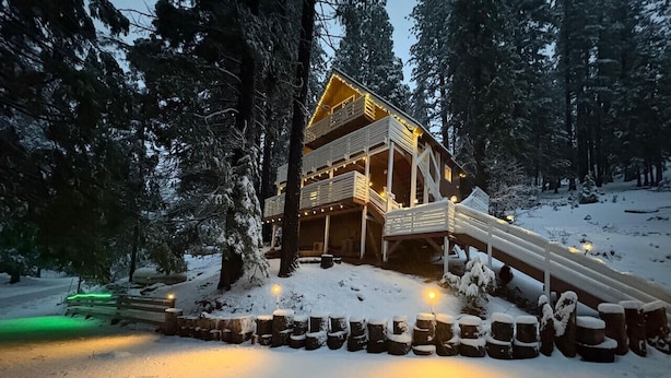 A cabin with a wooden exterior, multiple balconies, and a snow-covered landscape.