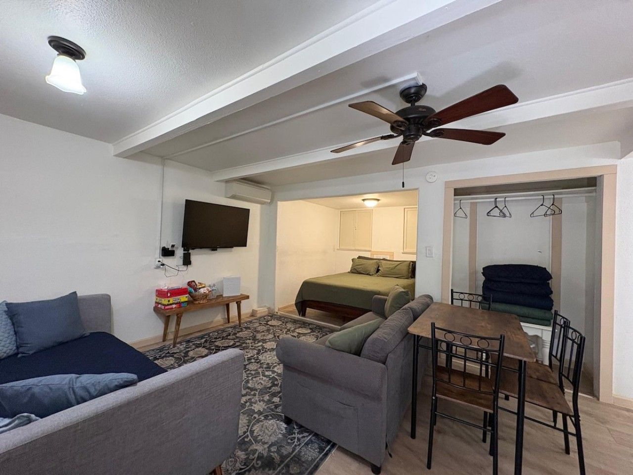 A compact living space with a sofa, a dining table, and a bed.