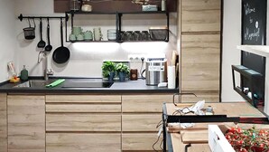 Una cocina moderna con armarios de madera, un lavamanos de acero inoxidable y una cafetera.