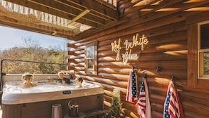 Una cabaña de madera con hidromasaje, banderas estadounidenses y un letrero de neón que dice "Red, White & Blue".
