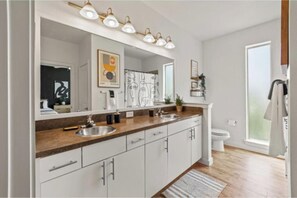 A modern bathroom with a large mirror, two sinks, and a toilet. - 2 BR|2 Baths| Heart of D/T, near AAC & Aquarium (Dallas)