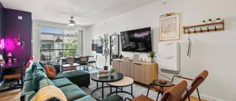 Un salon moderne avec un canapé, des fauteuils, une table basse et un téléviseur.