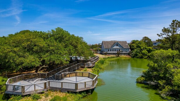 Ein Haus an einem Fluss mit einer Holzterrasse und einer Brücke.