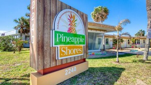 A sign for 'Pineapple Shores' with a beach theme, including a pineapple and palm trees. - Pineapple Shores Retro Inn 7 (Daytona Beach)