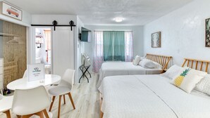 A hotel room with two beds, a desk, and a chair. There is a TV mounted on the wall and a sign that reads "SaltyDog Welcome Book". - Pineapple Shores Retro Inn 3 (Daytona Beach)