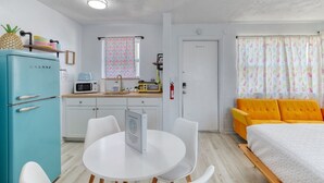 Une pièce compacte comprenant un coin cuisine, un espace repas et un lit.