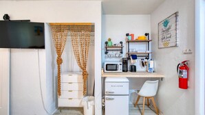 Une cuisine compacte équipée d’un four à micro-ondes, d’un petit réfrigérateur et d’un bureau en bois avec une chaise.
