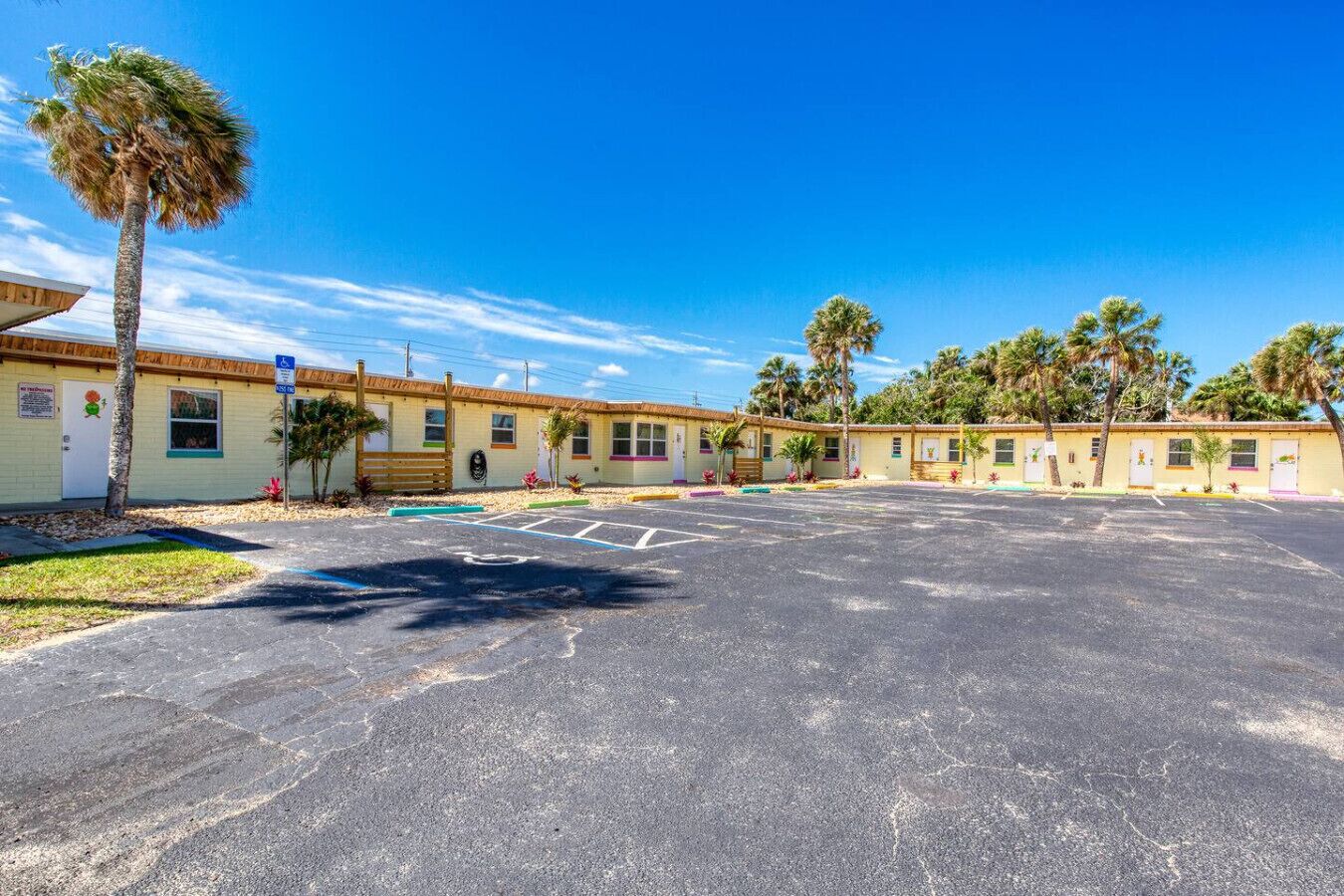 A motel with a parking lot, multiple rooms, and palm trees.