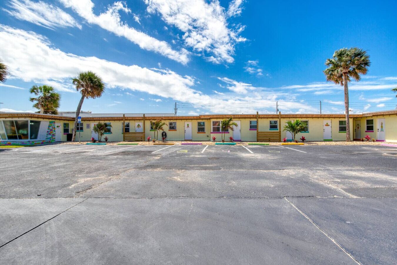 Un motel doté d’un grand parking, de nombreuses chambres et de palmiers.