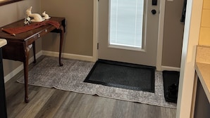 A hallway with a door, a small table with decorative items, a rug, and a framed picture on the wall. - 2-bedroom apartment in charming Austin. (Austin)