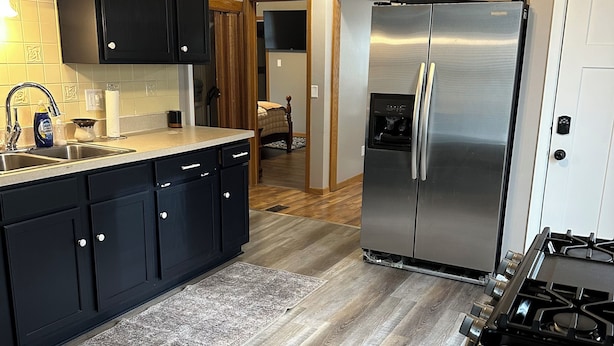 A modern kitchen with dark cabinets, a stainless steel refrigerator, and a gas stove. - 2-bedroom apartment in charming Austin. (Austin)