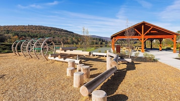 Un patio de recreo al aire libre con columpios, una estructura de madera y un área de picnic.