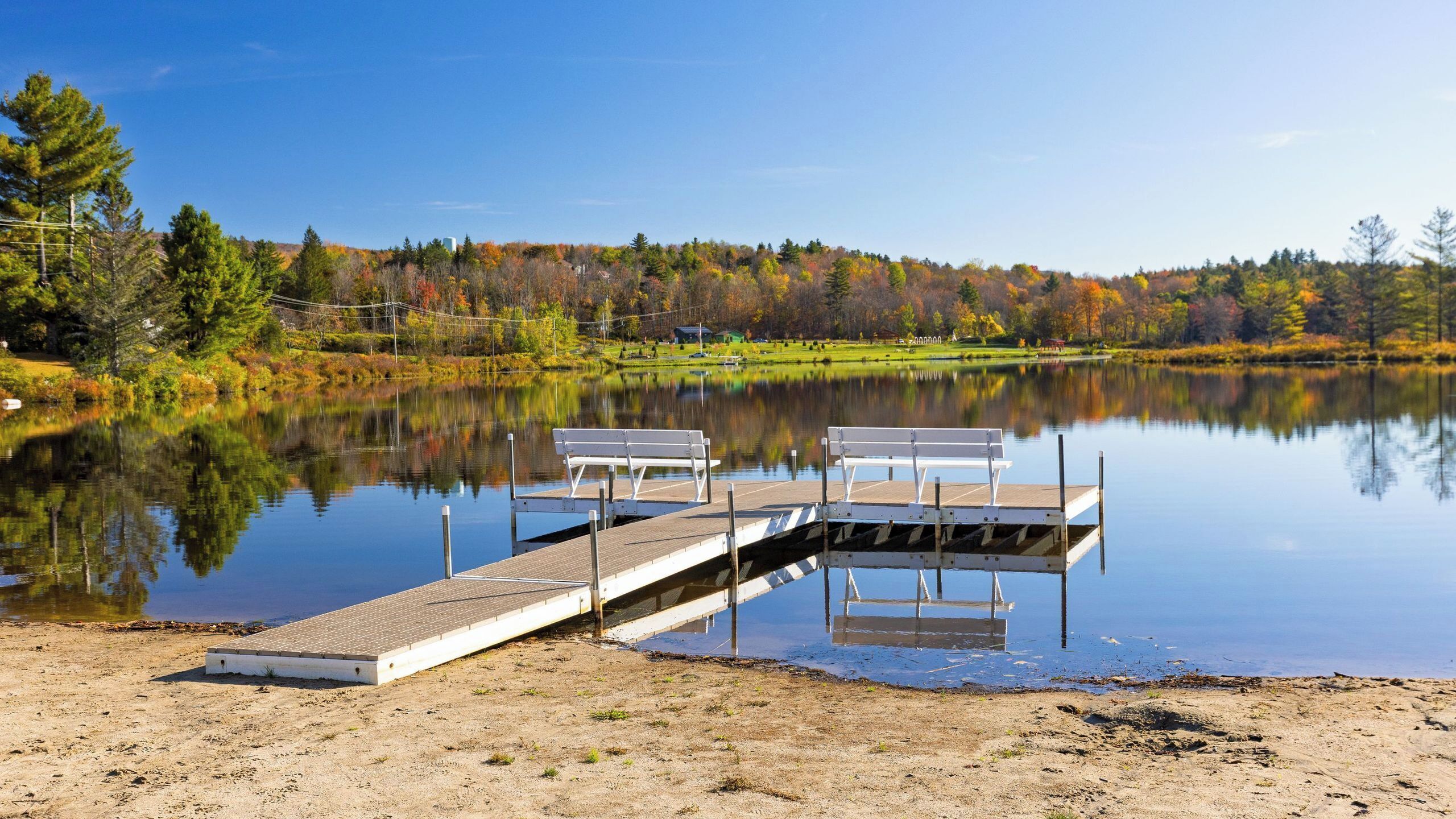 A calm lake with a wooden dock and benches.