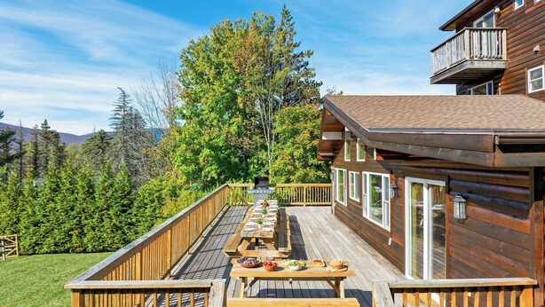 A wooden cabin with a deck, outdoor dining area, and a view of a forest and mountains. - Mins to Hunter Mountain Sleeps 36 Pool, Spa, Games & Bar Cozy Peaks Lodge by Avantstay (Tannersville)