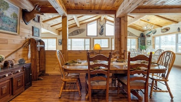 Un interior de madera con una mesa de comedor lista para cuatro personas, rodeada de sillas de madera.