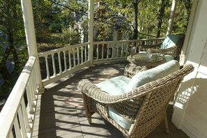A covered porch with wicker furniture and a white railing. - The Bamboo Suite (Eureka Springs)