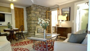 Una sala de estar con pared de piedra, una mesa de comedor con sillas, un sofá, una mesa auxiliar y una lámpara.