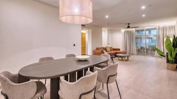 A modern living room with a dining area, including a table and chairs, a sofa set, and a large potted plant.