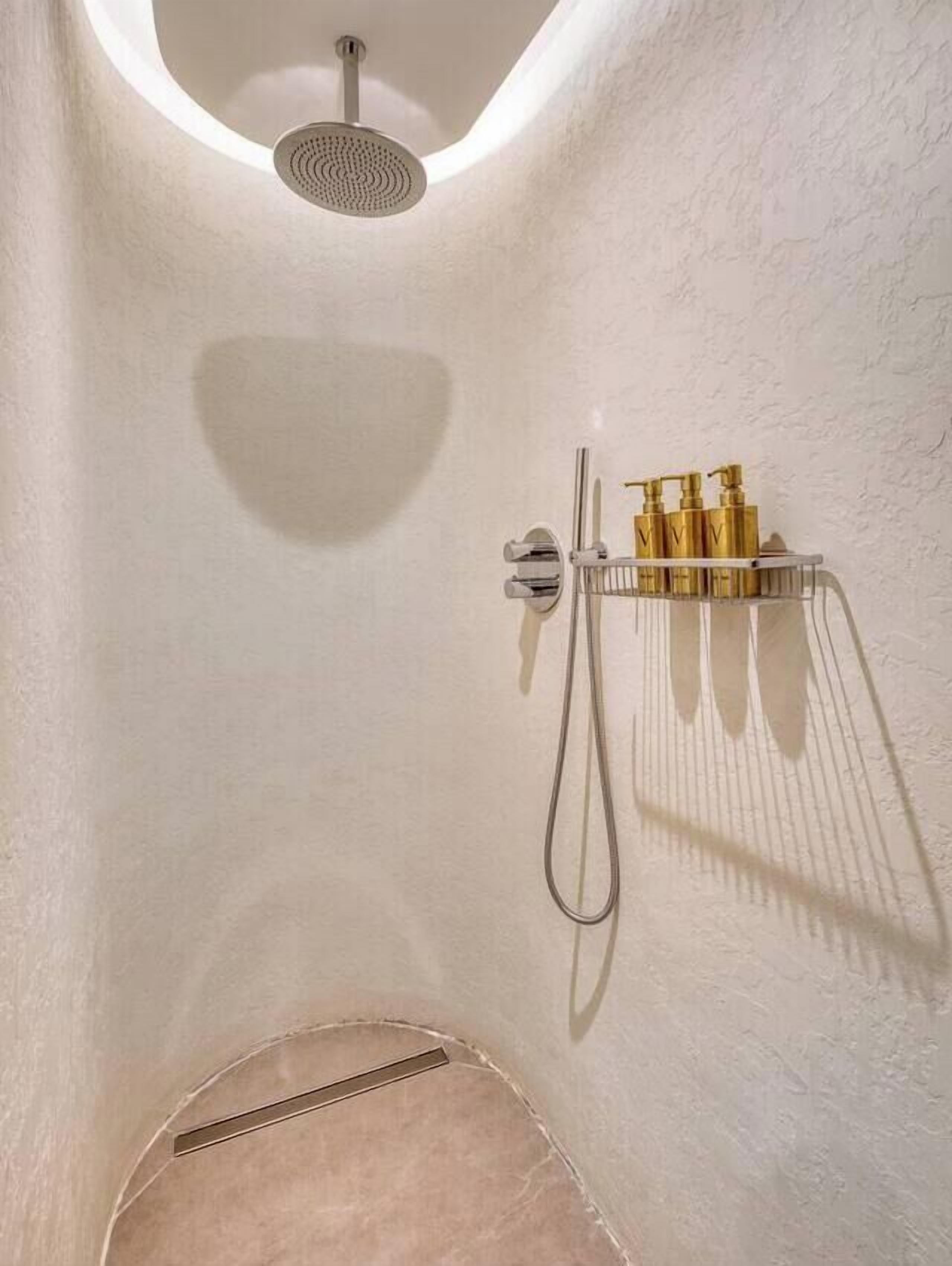 Ein modernes Badezimmer mit Dusche, Handtuchhalter und Ablagefläche für Toilettenartikel.