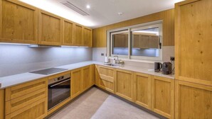 A modern kitchen with wooden cabinets, a built-in oven, a window, and a sink. - Elegant 2BR Retreat with Balcony & Fast Wi-Fi (Rabat)