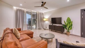 A modern living room with a leather sofa, a round coffee table, a TV, and a ceiling fan. - Elegant 2BR Retreat with Balcony & Fast Wi-Fi (Rabat)