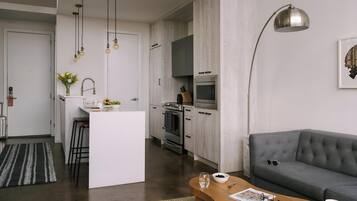 A modern kitchen with a central island, a dining area with a wooden table, and a grey sofa.
