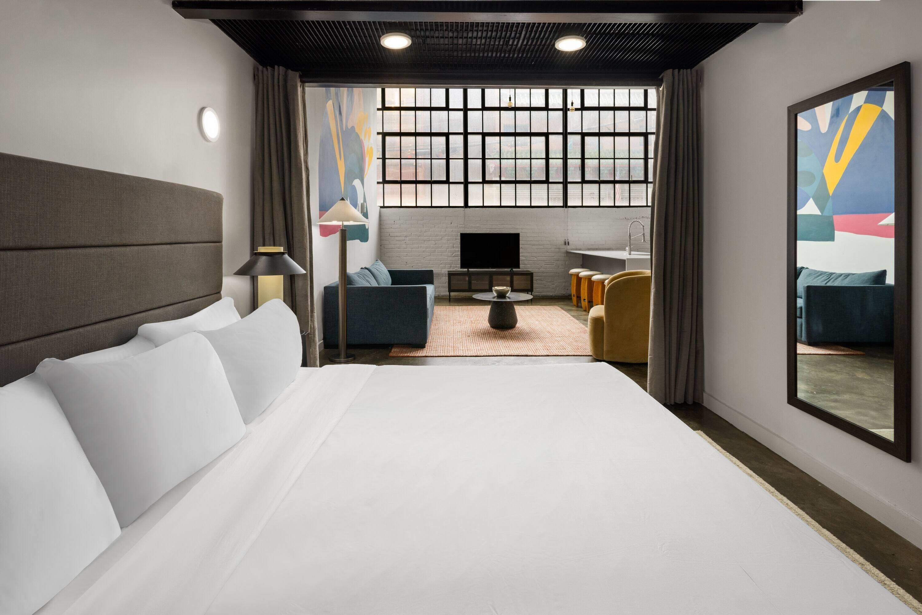 Une chambre d’hôtel moderne dotée d’un grand lit, d’un téléviseur à écran plat, d’un canapé et d’un coin repas.