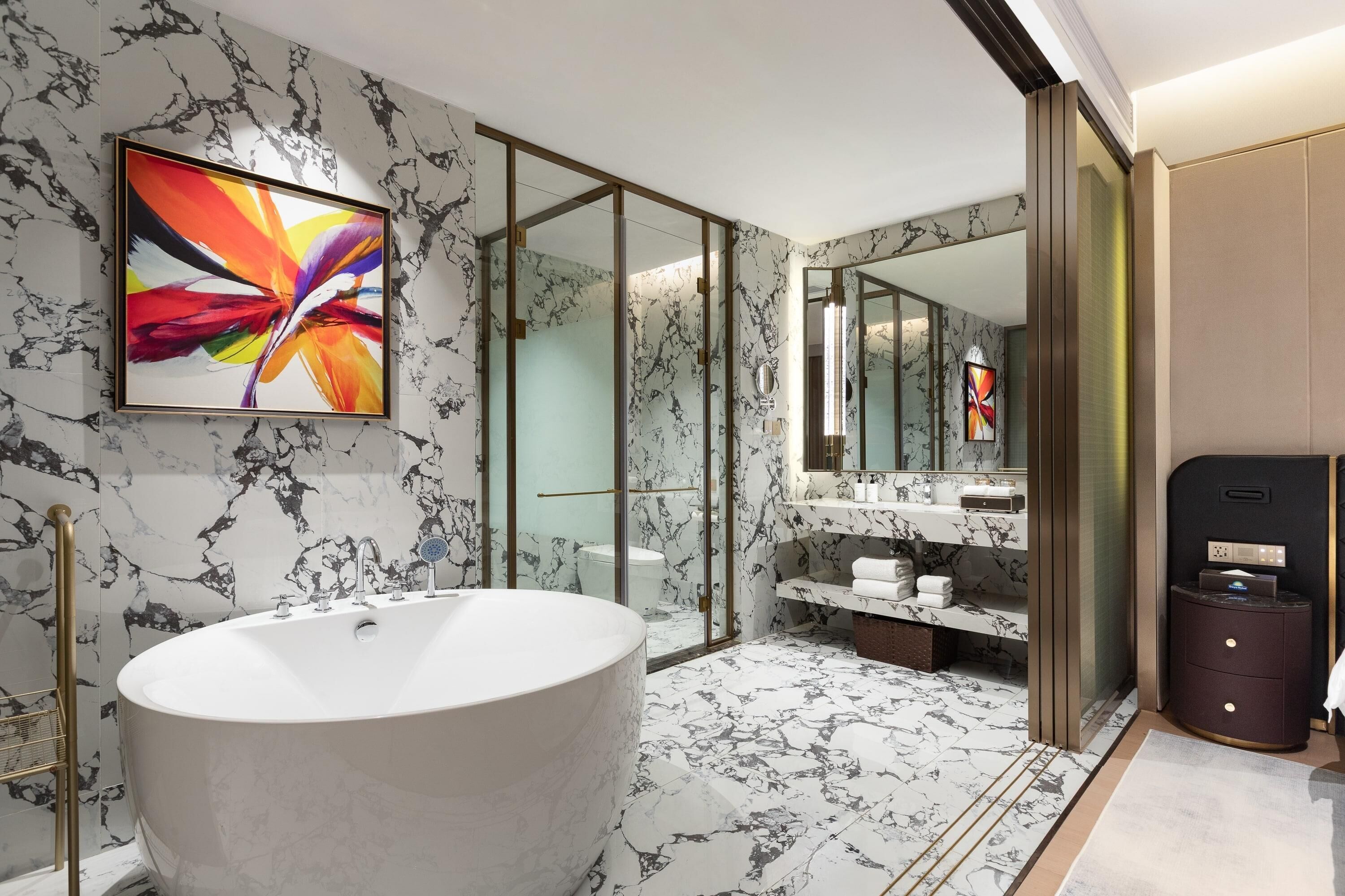Un baño moderno con una bañera independiente, un espejo grande y un suelo con diseño de mármol.