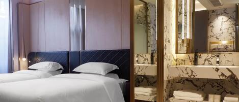 Una habitación de hotel con una cama grande, un baño independiente con tocador de mármol y un espejo.