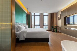 A modern hotel room with a large bed, a TV, a bathtub, and a city view. - Days Hotel By Wyndham Shantou Longhu (Shantou)