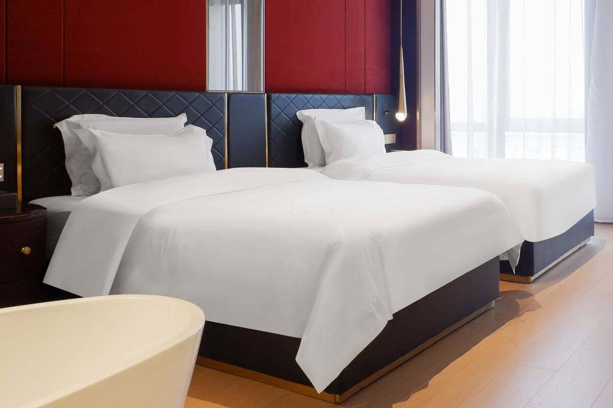 Una habitación de hotel con dos camas, un ventanal grande y un diseño moderno.