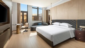 Une chambre d’hôtel moderne dotée d’un grand lit, d’un coin salon, d’une télévision et offrant une vue sur le désert.