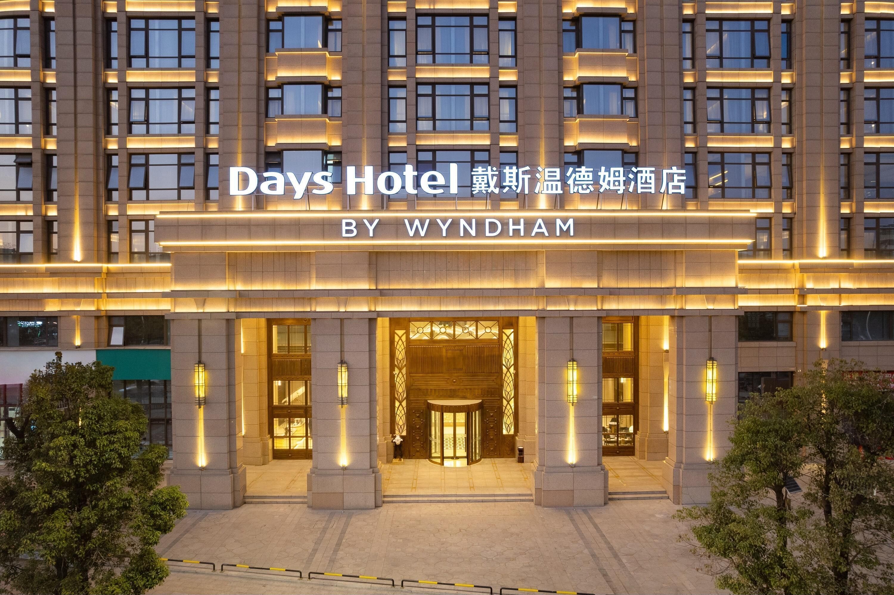 L'ingresso di un hotel con una facciata moderna, illuminato da luci calde, e un cartello che indica che si tratta di un Days Hotel by Wyndham.