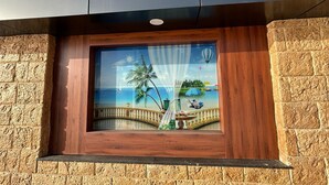 A framed picture of a beach scene with palm trees, a fence, and a hot air balloon.