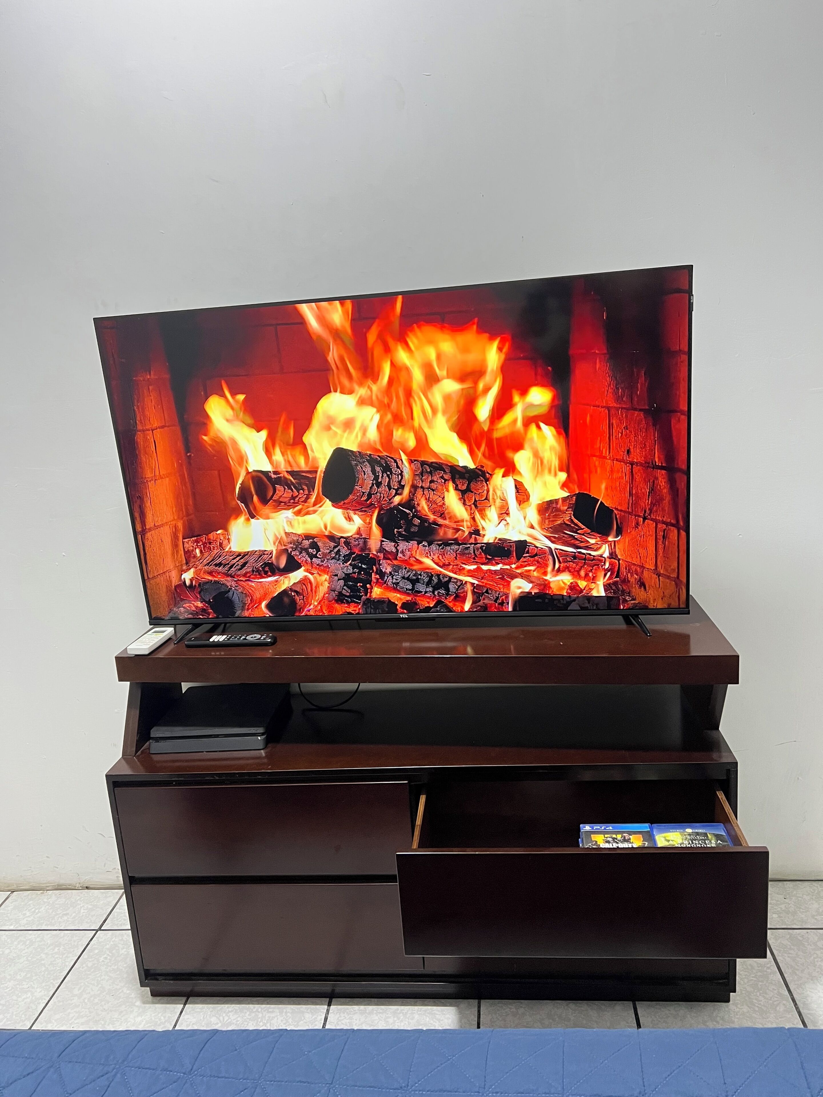 Un televisor de pantalla plana montado en un mueble de madera con chimenea empotrada mostrando fuego.