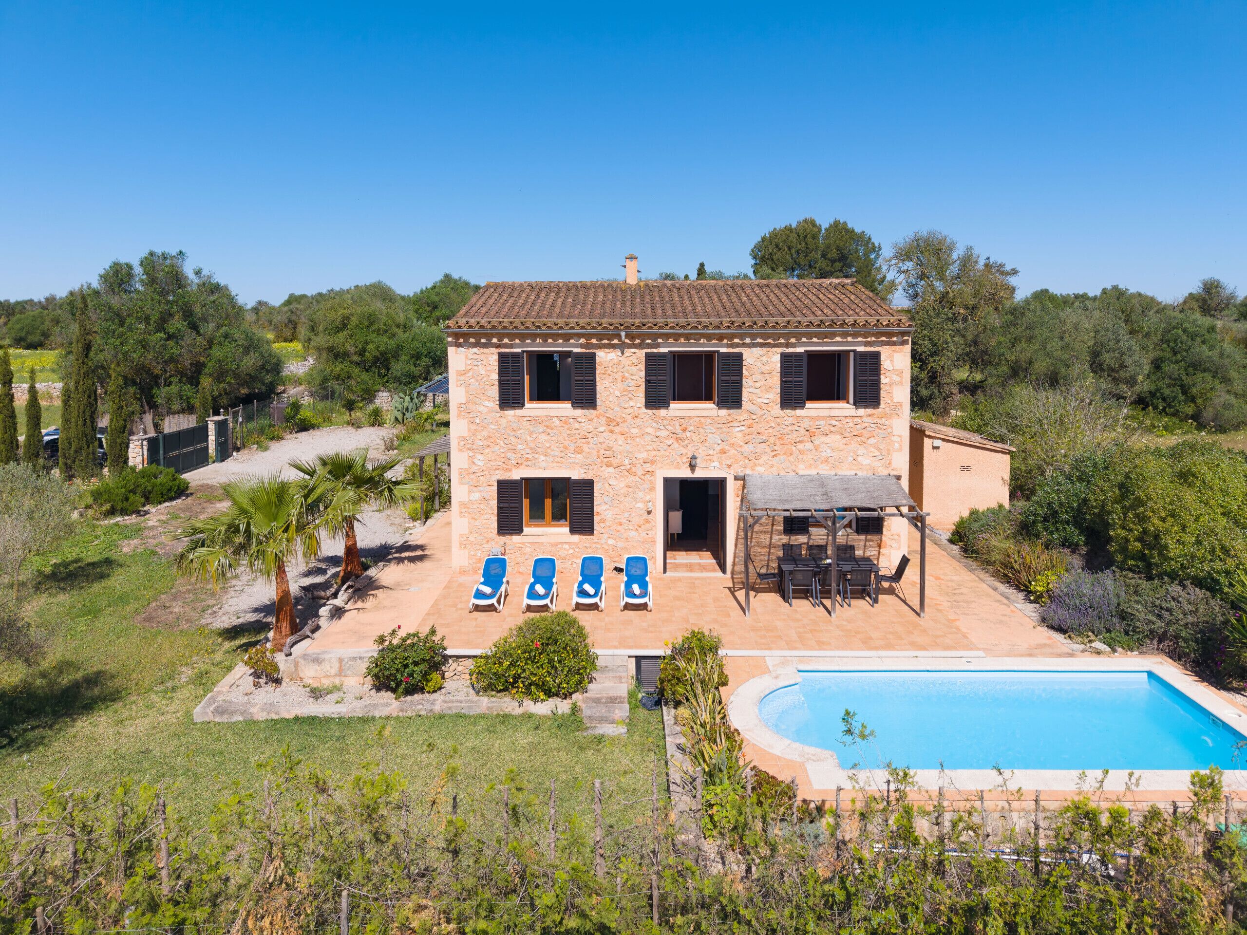 Una casa de piedra de dos pisos con piscina, mobiliario de exterior y jardín.