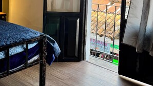 A room with a bed, a sliding glass door leading to a balcony, and a view of the outside. - Antica Casa Dáttoli (Cuetzalan del Progreso)