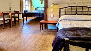 A rustic room with a wooden ceiling, a bed with a patterned bedspread, a wooden table with chairs, and a bench. - Antica Casa Dáttoli (Cuetzalan del Progreso)