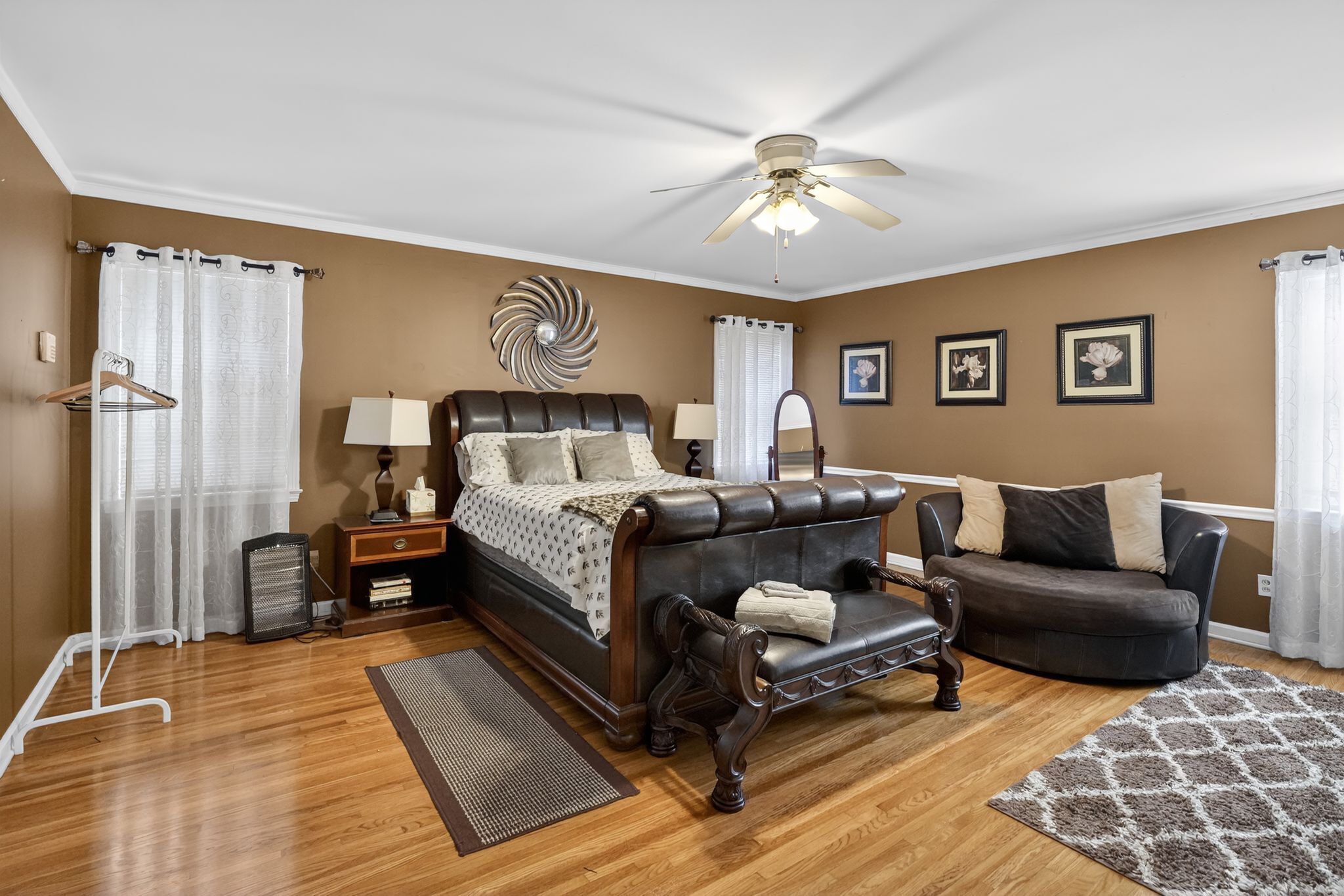 Une chambre à coucher avec un lit, un canapé, un ventilateur de plafond et un tapis.