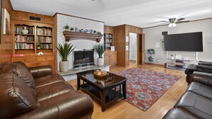 Un salon doté d’une cheminée, de bibliothèques, de canapés en cuir, d’une table basse et d’un téléviseur à écran plat.