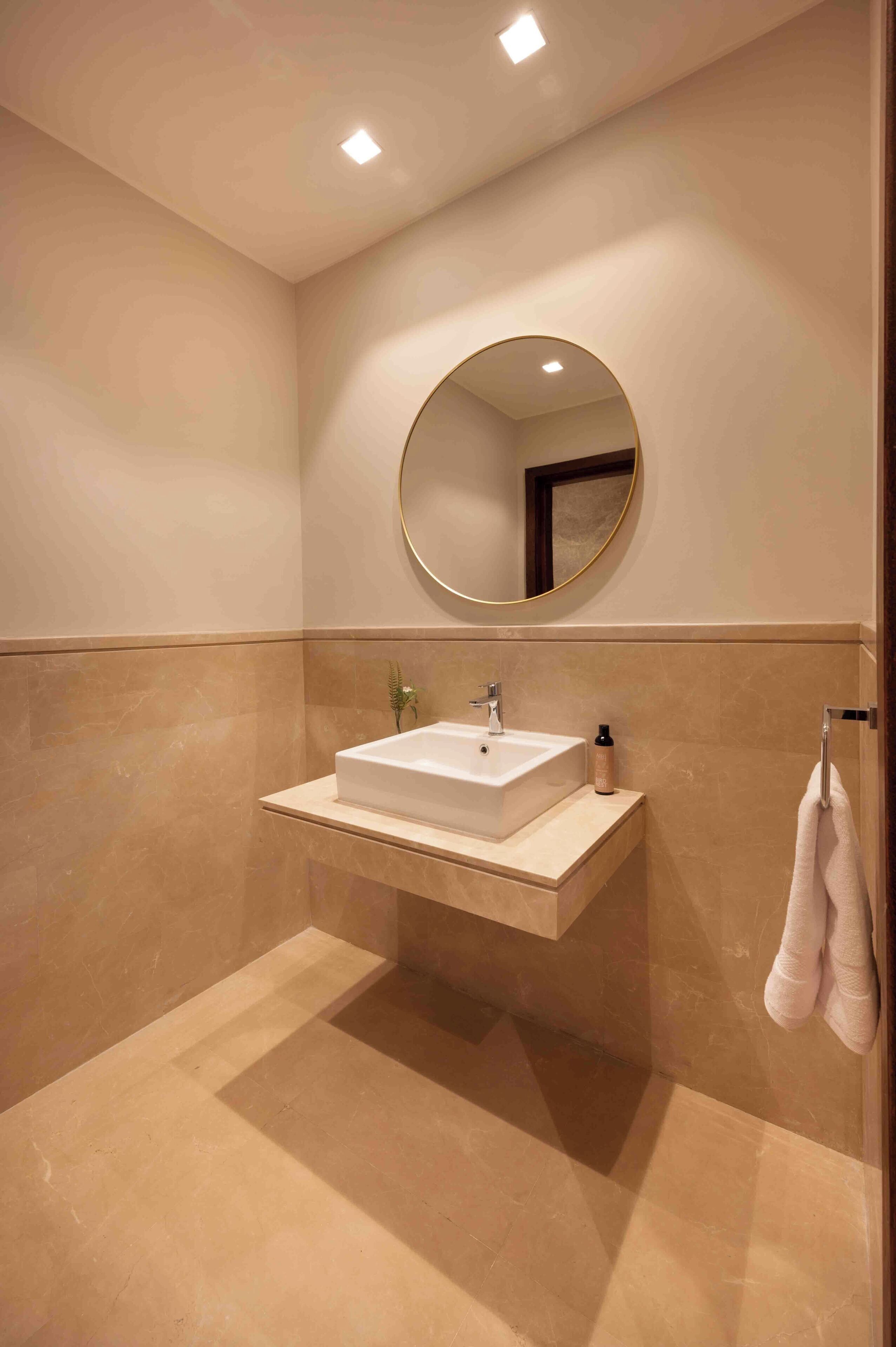 Une salle de bain moderne avec un lavabo rectangulaire, un miroir rond et un porte-serviettes.