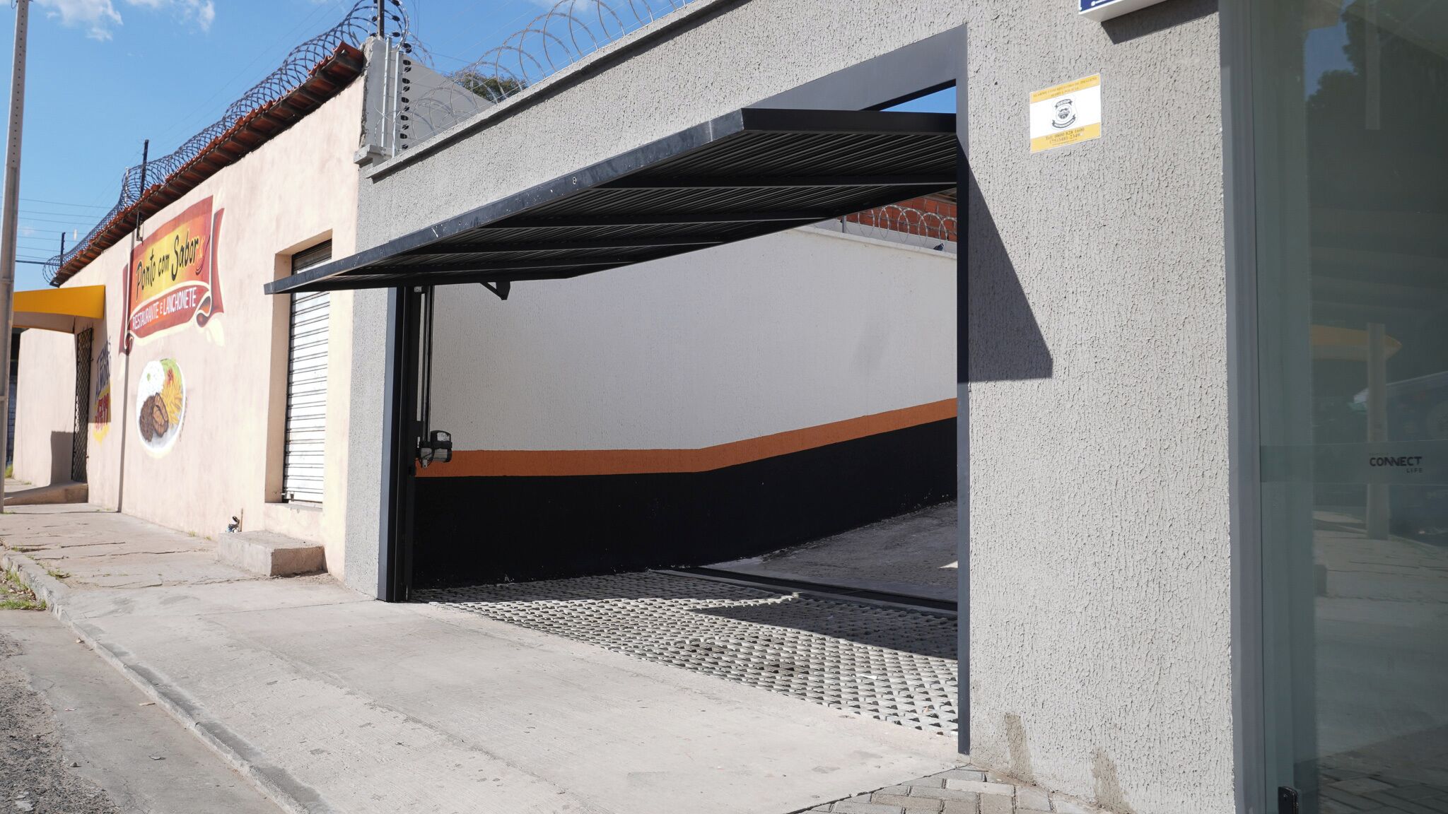 A building with a garage door, a small entrance, and a sign indicating a restaurant.