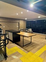 Cocina moderna con pared de ladrillo, una mesa de comedor de madera y un amplio ventanal con vista a un paisaje urbano.