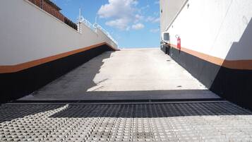 A concrete ramp leading to a building with a white and orange stripe design, a fire extinguisher, and a clear sky.