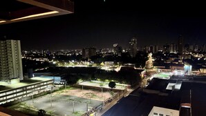 Paisatge urbà nocturn amb edificis il·luminats i un camp esportiu.