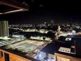 Un paisaje urbano nocturno con edificios iluminados y un campo deportivo.