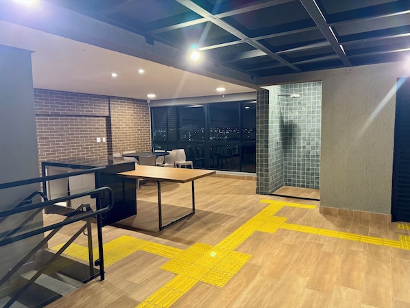 A modern interior with a brick wall, a large window offering a city view, and a yellow tactile path on the floor.