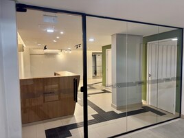 Un área de recepción moderna con un mostrador de madera, puertas de vidrio y suelo de baldosas.